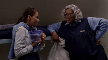 Movie still from “Madea Goes to Jail” (2009), directed by Tyler Perry – Two women are talking to each other while holding a plastic container; Medium shot, Over the shoulder angle