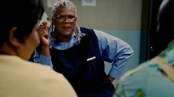 Movie still from “Madea Goes to Jail” (2009), directed by Tyler Perry – A person with a long dreadlocks sitting in a room; Close Up shot, Over the shoulder angle