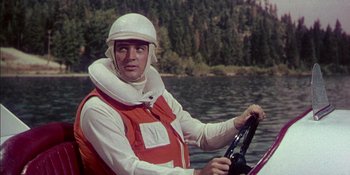 Movie still from “Magnificent Obsession” (1954), directed by Douglas Sirk – A man in a life jacket driving a boat in the water; Medium shot, Over the shoulder angle