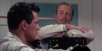Movie still from “Magnificent Obsession” (1954), directed by Douglas Sirk – Two men sitting next to each other in front of a radio; Close Up shot, Over the shoulder angle