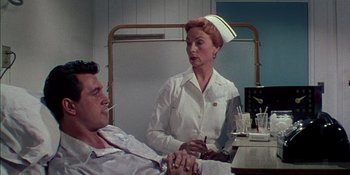 Movie still from “Magnificent Obsession” (1954), directed by Douglas Sirk – A nurse talking to a patient in a hospital room; Medium shot, Low angle