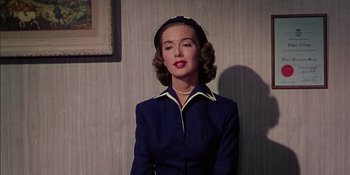 Movie still from “Magnificent Obsession” (1954), directed by Douglas Sirk – A woman wearing a blue suit with a veil on her head; Medium shot, Low angle