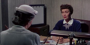 Movie still from “Magnificent Obsession” (1954), directed by Douglas Sirk – A woman sitting in front of another woman in front of a television; Medium shot, Over the shoulder angle