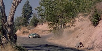 Movie still from “Magnificent Obsession” (1954), directed by Douglas Sirk – A car driving down a road next to trees; Extreme Wide shot, High angle
