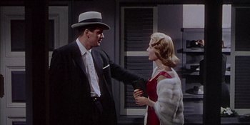 Movie still from “Magnificent Obsession” (1954), directed by Douglas Sirk – A man in a suit and a woman in a red dress; Medium shot, Low angle