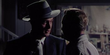 Movie still from “Magnificent Obsession” (1954), directed by Douglas Sirk – A man in a suit and a hat talking to another man in a suit and a hat; Close Up shot, Over the shoulder angle