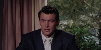 Movie still from “Magnificent Obsession” (1954), directed by Douglas Sirk – A person wearing a suit and tie; Close Up shot, Over the shoulder angle