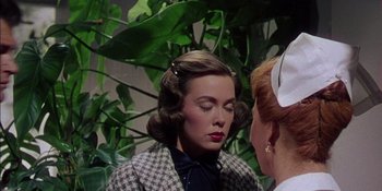 Movie still from “Magnificent Obsession” (1954), directed by Douglas Sirk – A woman in a checkered jacket is talking to another woman; Close Up shot, Over the shoulder angle