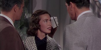 Movie still from “Magnificent Obsession” (1954), directed by Douglas Sirk – A young woman is looking at a man in a black and white checkered suit; Close Up shot, Over the shoulder angle