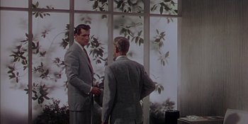 Movie still from “Magnificent Obsession” (1954), directed by Douglas Sirk – Two men in business suits standing in front of a window; Medium shot, Low angle