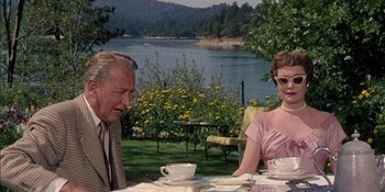 Movie still from “Magnificent Obsession” (1954), directed by Douglas Sirk – A man and a woman sitting at a table with a lake in the background; Medium shot, Over the shoulder angle