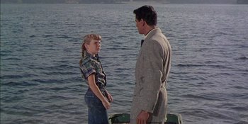 Movie still from “Magnificent Obsession” (1954), directed by Douglas Sirk – A man and a little girl standing in front of a body of water; Medium shot, Over the shoulder angle