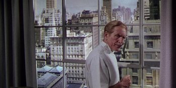 Movie still from “Magnificent Obsession” (1954), directed by Douglas Sirk – An older man standing in front of a large window; Medium shot, Low angle