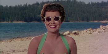 Movie still from “Magnificent Obsession” (1954), directed by Douglas Sirk – A woman wearing a green bathing suit and sunglasses; Close Up shot, Low angle