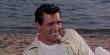 Movie still from “Magnificent Obsession” (1954), directed by Douglas Sirk – A person smiling near the water; Close Up shot, Low angle