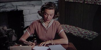 Movie still from “Magnificent Obsession” (1954), directed by Douglas Sirk – A woman sitting at a table writing on a piece of paper; Medium shot, High angle