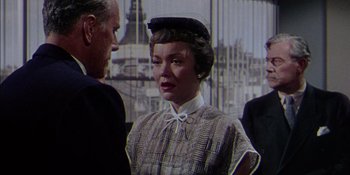 Movie still from “Magnificent Obsession” (1954), directed by Douglas Sirk – An older woman wearing a hat standing next to an older man; Medium shot, Over the shoulder angle