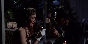 Movie still from “Magnificent Obsession” (1954), directed by Douglas Sirk – A man and a woman drinking wine at a party; Medium shot, Low angle
