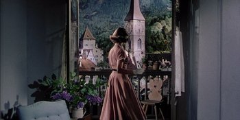 Movie still from “Magnificent Obsession” (1954), directed by Douglas Sirk – A woman standing in front of a painting of a church; Wide shot, Low angle