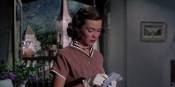 Movie still from “Magnificent Obsession” (1954), directed by Douglas Sirk – A woman wearing gloves and holding a book; Medium shot, Low angle