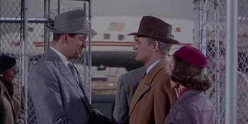 Movie still from “Magnificent Obsession” (1954), directed by Douglas Sirk – Two men and a woman wearing hats talking to each other; Medium shot, Over the shoulder angle