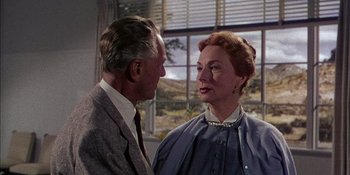 Movie still from “Magnificent Obsession” (1954), directed by Douglas Sirk – An older man standing next to an older woman in front of a window; Close Up shot, Over the shoulder angle