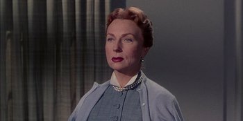 Movie still from “Magnificent Obsession” (1954), directed by Douglas Sirk – An older woman wearing a blue dress and a pearl necklace; Close Up shot, Low angle