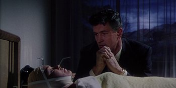 Movie still from “Magnificent Obsession” (1954), directed by Douglas Sirk – A man sitting next to a woman on a bed; Medium shot, Low angle