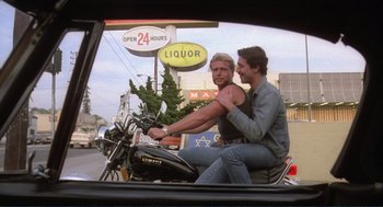 Movie still from “Making Love” (1982), directed by Arthur Hiller – Two men riding a motorcycle in the back of a car; Medium shot, Low angle