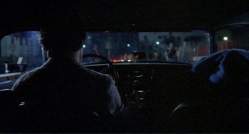 Movie still from “Making Love” (1982), directed by Arthur Hiller – A person sitting in the driver's seat of a car at night; Wide shot, Over the shoulder angle