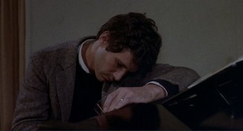 Movie still from “Making Love” (1982), directed by Arthur Hiller – A man sitting at a table with his head resting on his hand; Close Up shot, High angle