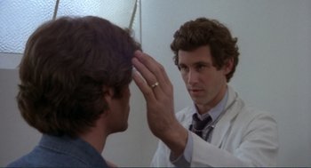 Movie still from “Making Love” (1982), directed by Arthur Hiller – A man in a white lab coat looking in the mirror; Close Up shot, Over the shoulder angle