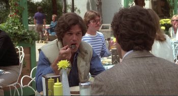 Movie still from “Making Love” (1982), directed by Arthur Hiller – A man is eating a piece of cake at a table; Medium shot, Over the shoulder angle