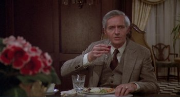 Movie still from “Making Love” (1982), directed by Arthur Hiller – An older man sitting at a dinner table drinking a glass of wine; Medium shot, Over the shoulder angle