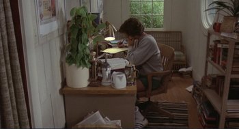 Movie still from “Making Love” (1982), directed by Arthur Hiller – A woman sitting at a desk writing on a piece of paper; Wide shot, High angle