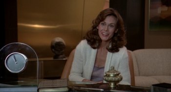Movie still from “Making Love” (1982), directed by Arthur Hiller – A woman sitting at a table in a room; Medium shot, Over the shoulder angle