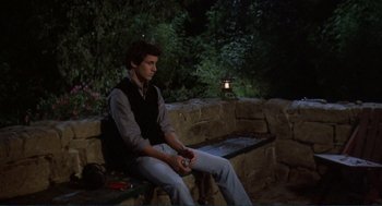 Movie still from “Making Love” (1982), directed by Arthur Hiller – A man sitting on top of a wooden bench at night; Medium shot, High angle