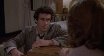 Movie still from “Making Love” (1982), directed by Arthur Hiller – A man sitting at a table in front of a woman; Close Up shot, High angle