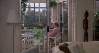 Movie still from “Making Love” (1982), directed by Arthur Hiller – A man sitting on a chair in a living room; Wide shot, High angle