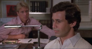 Movie still from “Making Love” (1982), directed by Arthur Hiller – Two men sitting at a table with papers on the table; Close Up shot, Over the shoulder angle