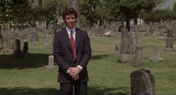 Movie still from “Making Love” (1982), directed by Arthur Hiller – A man in a suit standing in front of a cemetery; Medium shot, Low angle