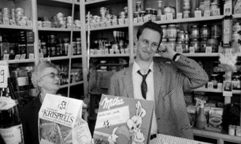 Movie still from “Man Bites Dog” (1992), directed by Benoît Poelvoorde – A black and white photo of a man in a store; Medium shot, Over the shoulder angle