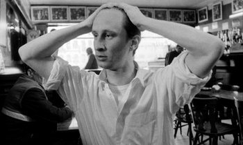 Movie still from “Man Bites Dog” (1992), directed by Benoît Poelvoorde – A black - and - white photo of a man holding his head; Close Up shot, Low angle