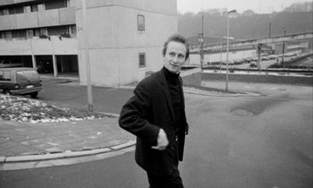 Movie still from “Man Bites Dog” (1992), directed by Benoît Poelvoorde – A black and white photo of a man walking down the street; Medium shot, Low angle