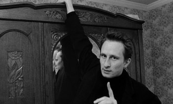 Movie still from “Man Bites Dog” (1992), directed by Benoît Poelvoorde – A black and white photo of a man holding his hand up; Close Up shot, Low angle