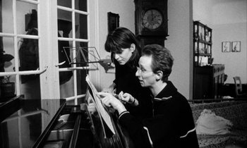 Movie still from “Man Bites Dog” (1992), directed by Benoît Poelvoorde – A woman and a man are looking at a sheet of paper; Medium shot, High angle