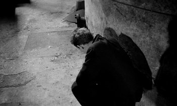 Movie still from “Man Bites Dog” (1992), directed by Benoît Poelvoorde – A man leaning against a wall on the side of the street; Wide shot, High angle