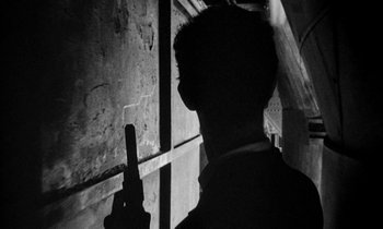 Movie still from “Man Bites Dog” (1992), directed by Benoît Poelvoorde – A man holding a cell phone in his hand; Close Up shot, Low angle