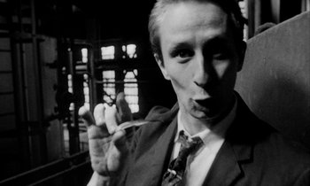 Movie still from “Man Bites Dog” (1992), directed by Benoît Poelvoorde – A black and white photo of a man smoking a cigarette; Close Up shot, Low angle