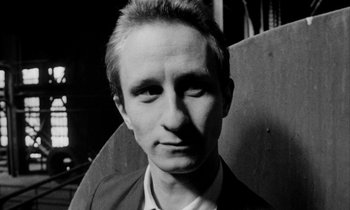 Movie still from “Man Bites Dog” (1992), directed by Benoît Poelvoorde – Black and white photograph of a man in a suit; Close Up shot, Low angle